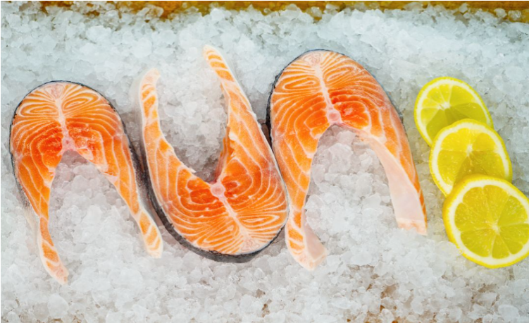 Atlantic salmon cutlets on a bed of ice with lemon slices.