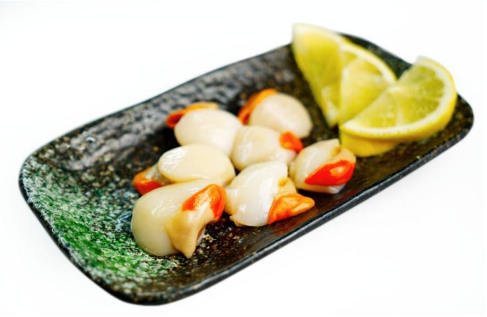 Plated Scallops with lemon wedges on a white background