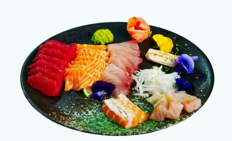Assorted sashimi on a black plate with garnishes