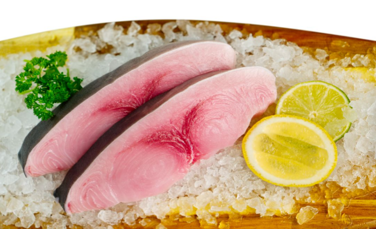 Swordfish fillets on a bed of salt with lemon and parsley garnish.